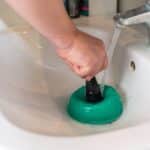hand held plunger being used on sink blockage