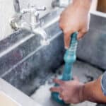 technician with hand held plunger at sink blockage